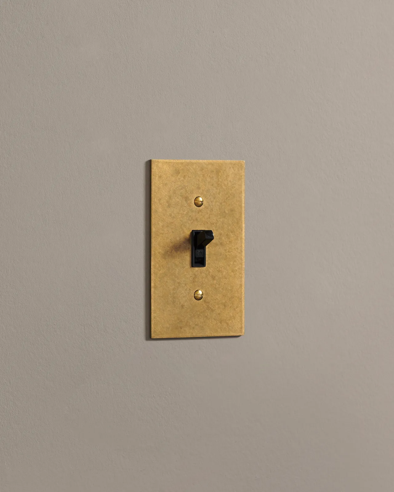 A side on shot on a toggle switch on an aged brass cover plate.