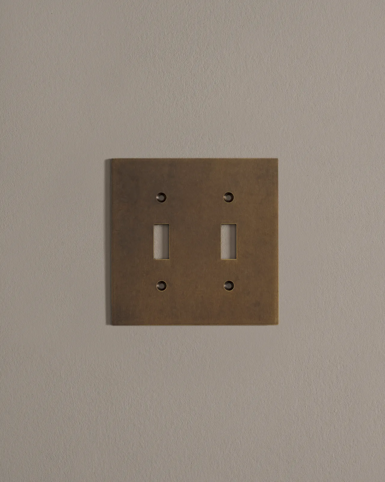 a front on shot of the toggle switch cover plate in oxidised brass finish.