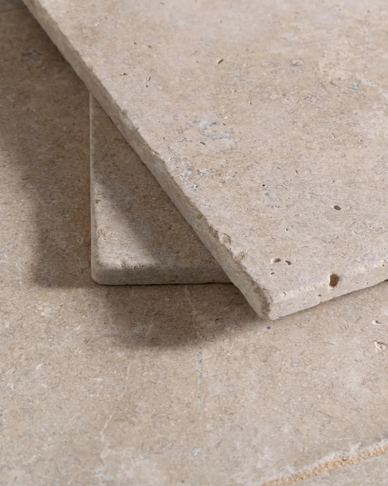 a close up image of the dijon tumbled limestone, looking soft and warm cream, with two tiles stacked together.