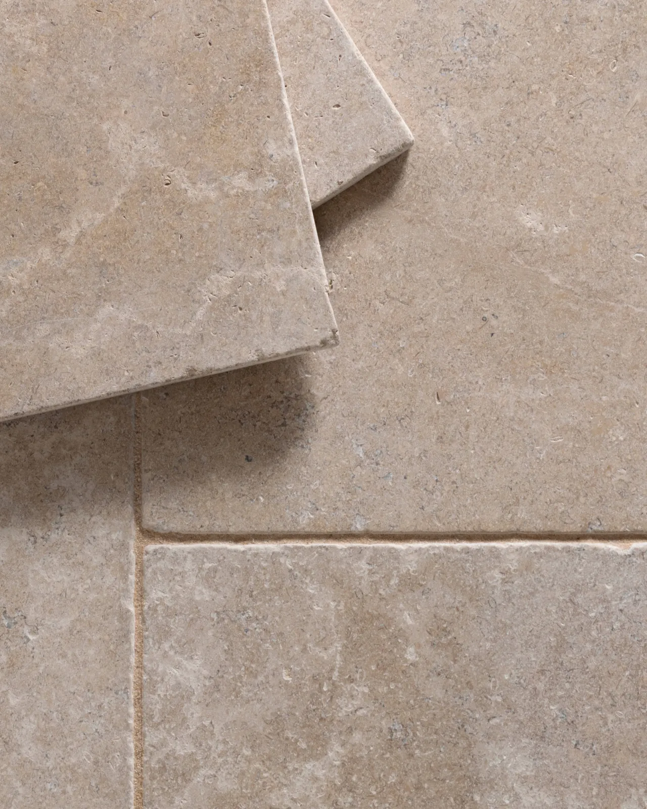 a top down image of the dijon tumbled limestone, looking soft and warm cream, with two tiles stacked together.