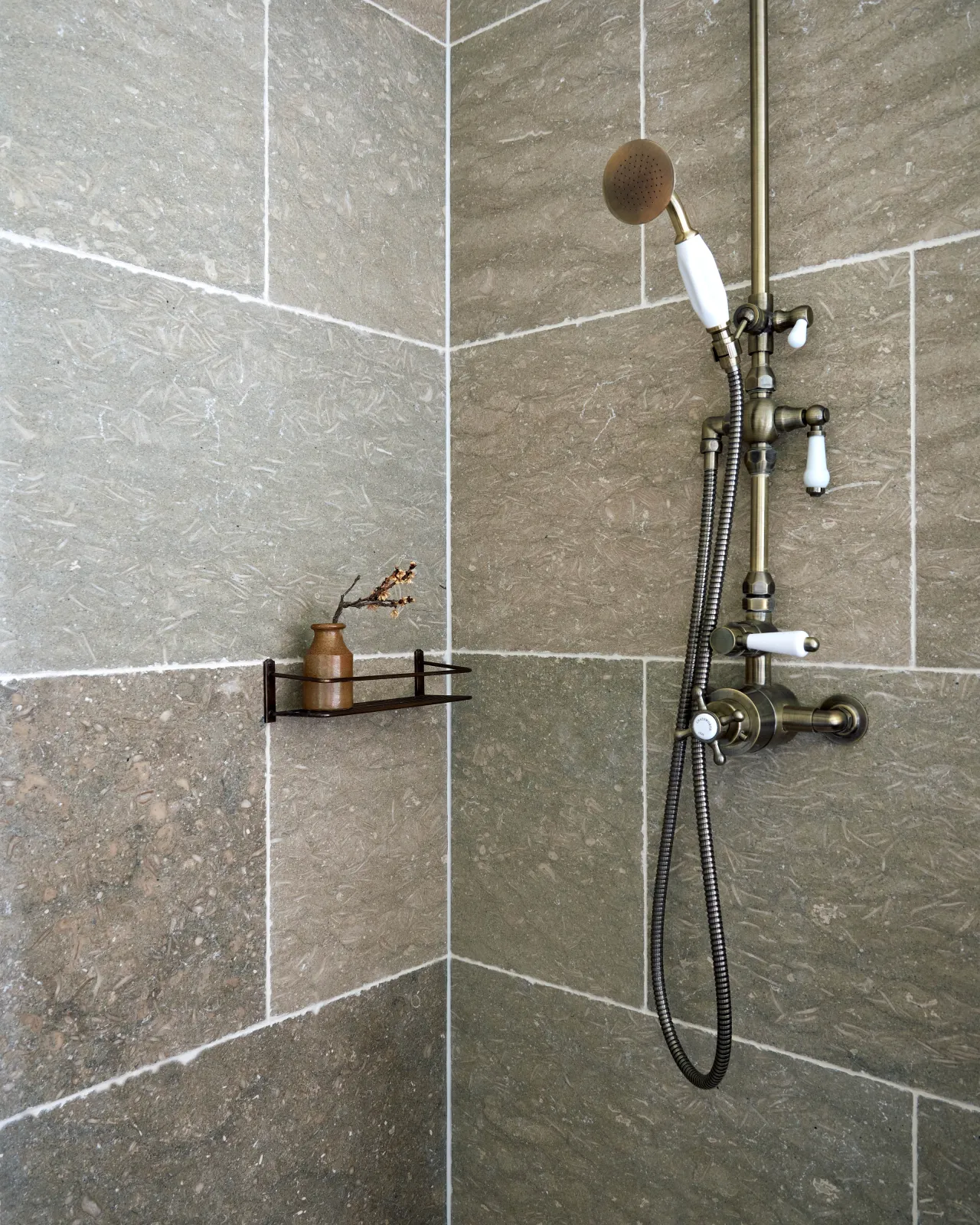 A shower with Seagrass Tumbled Limestone tiled walls.