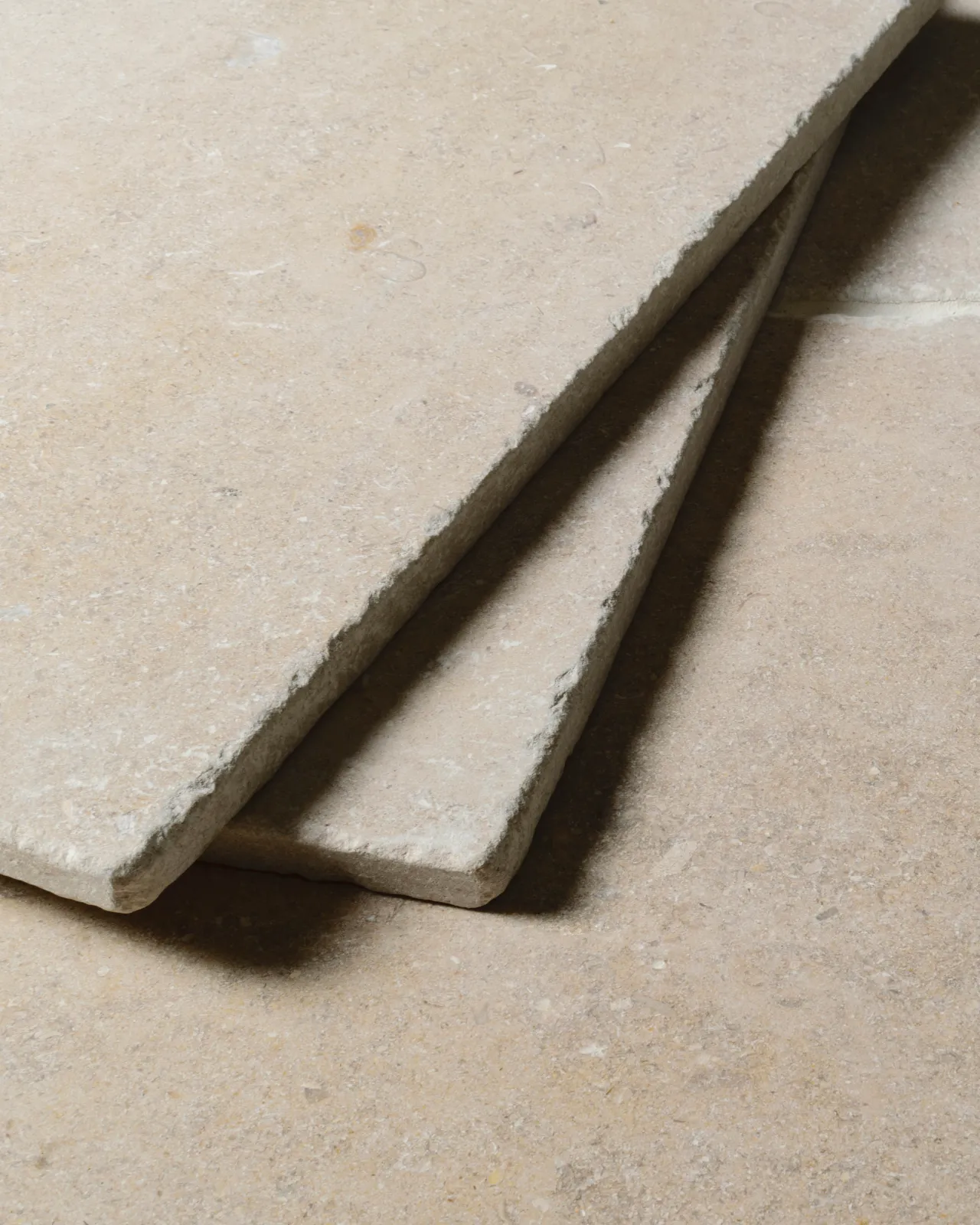 A close-up view of two loose Vintage Bronze Limestone tiles.