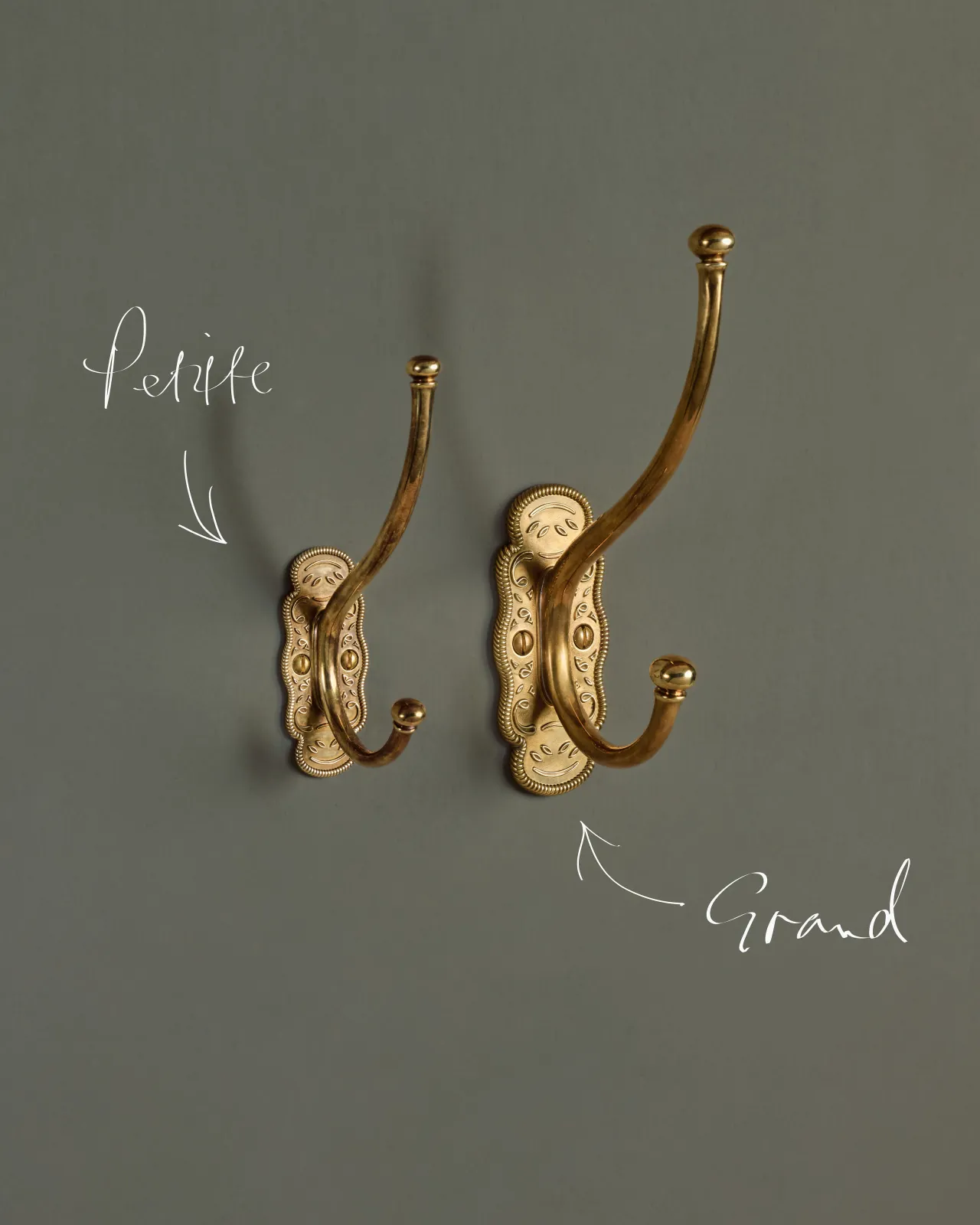 the petite and grand parisian cafe coat hook on a green-ish grey wall, side by side to show the size difference.