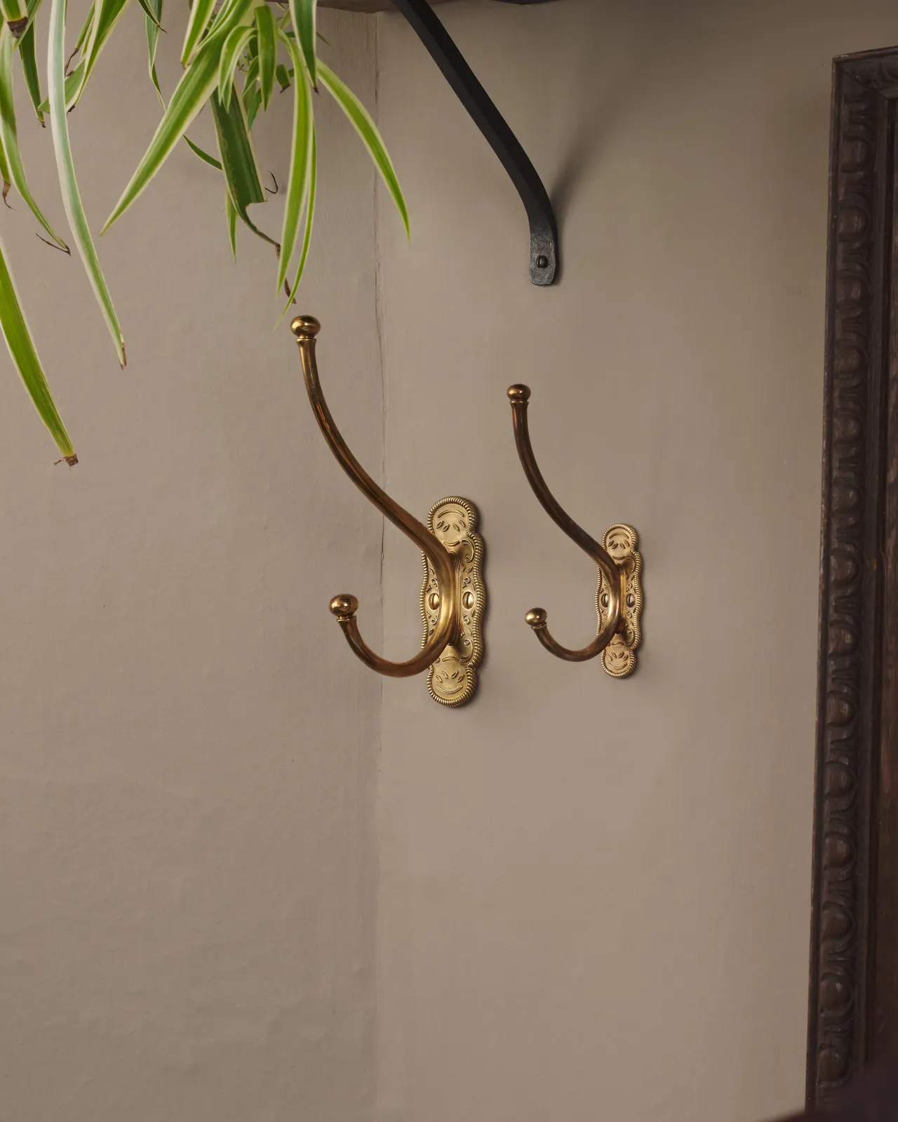 the two parisian cafe coat hook hung on a grey wall, showing the size difference.