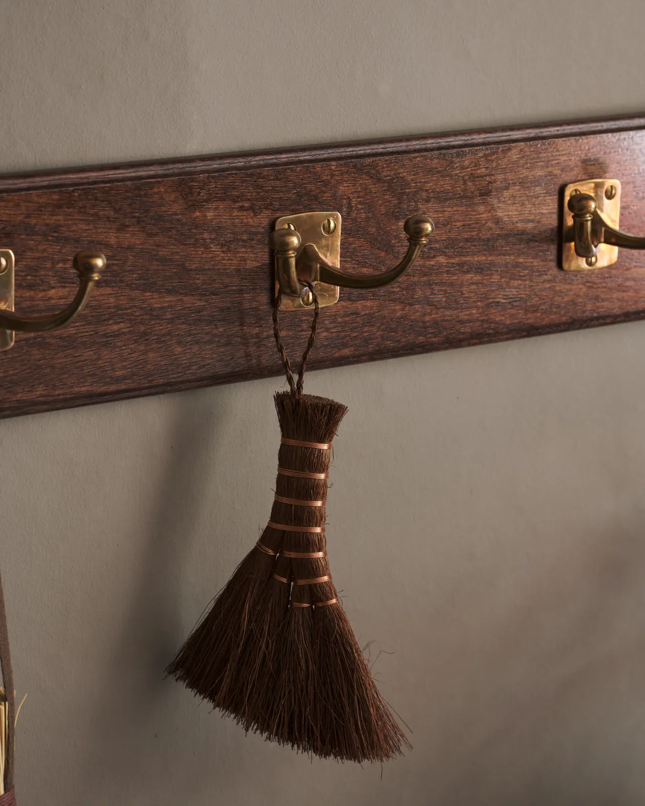 A close-up detailed view of a Mahogany Finish backboard with three brass Twin Edwardian Hooks.