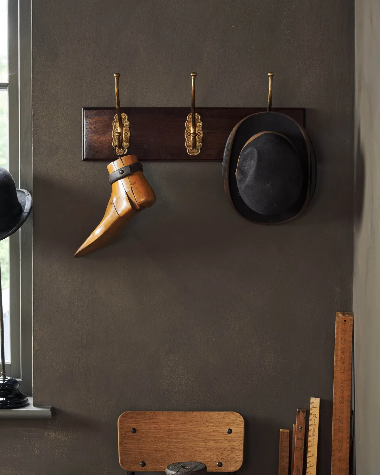 A Mahogany Finish Hook Rack with three brass Grand Parisian Café Hooks, fitted to a dark corner with a bowler hat and a vintage wooden shoe tree hanging.