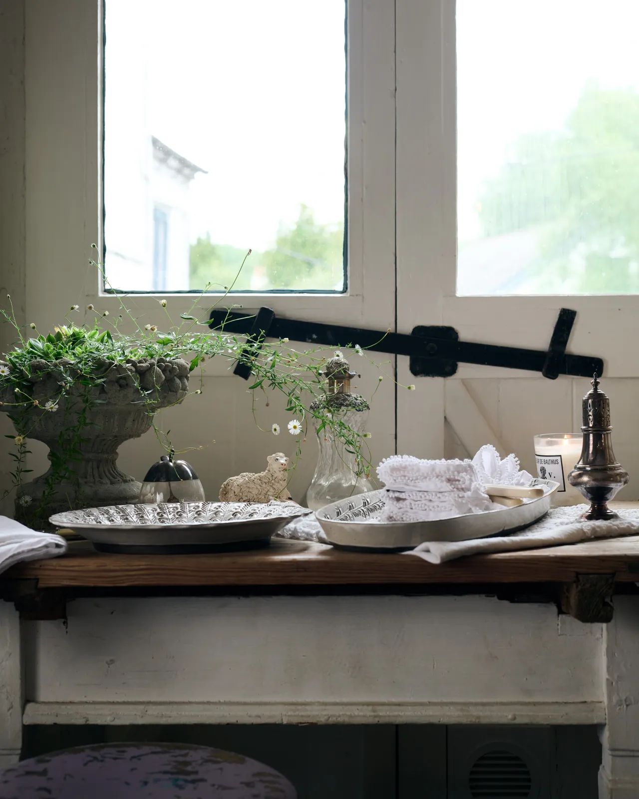 A profile view of two bohemian-style white ceramic platters on a vintage farmhouse table.