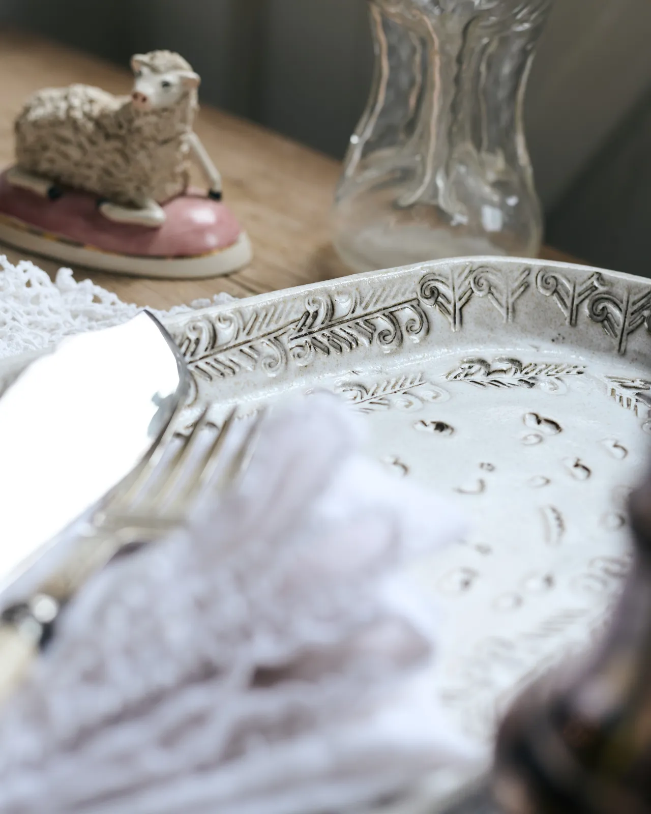 A close-up view of delicate impressions and surface patterns on an oval-shaped handmade bohemian-style white ceramic platter.