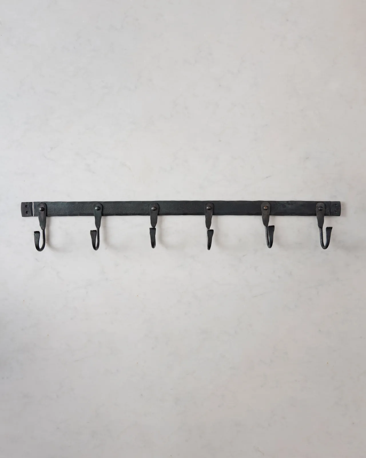 A large iron hook rack with six hooks spread evenly across the length.