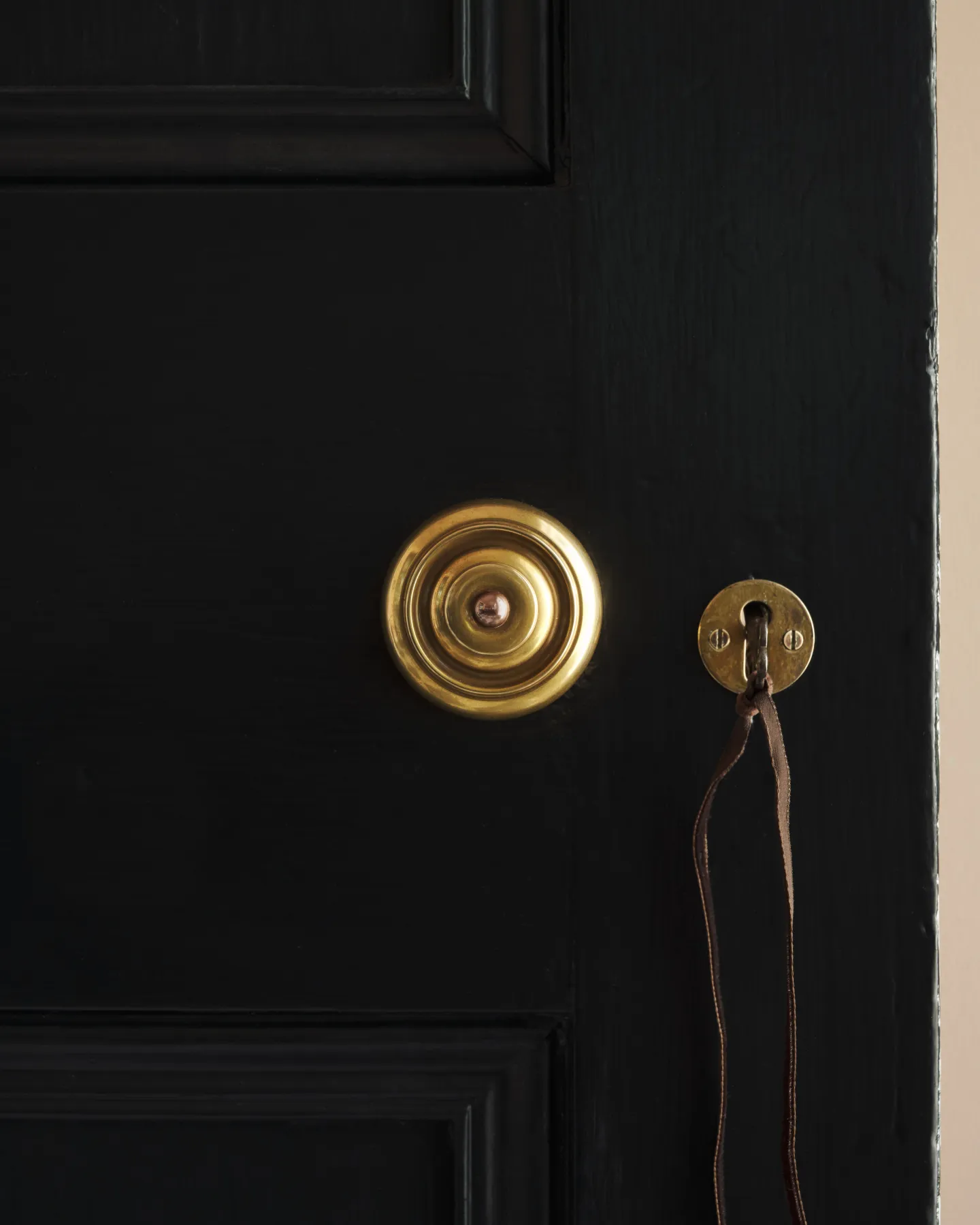 A close detail of the brass doorknob, set against the black-painted door.