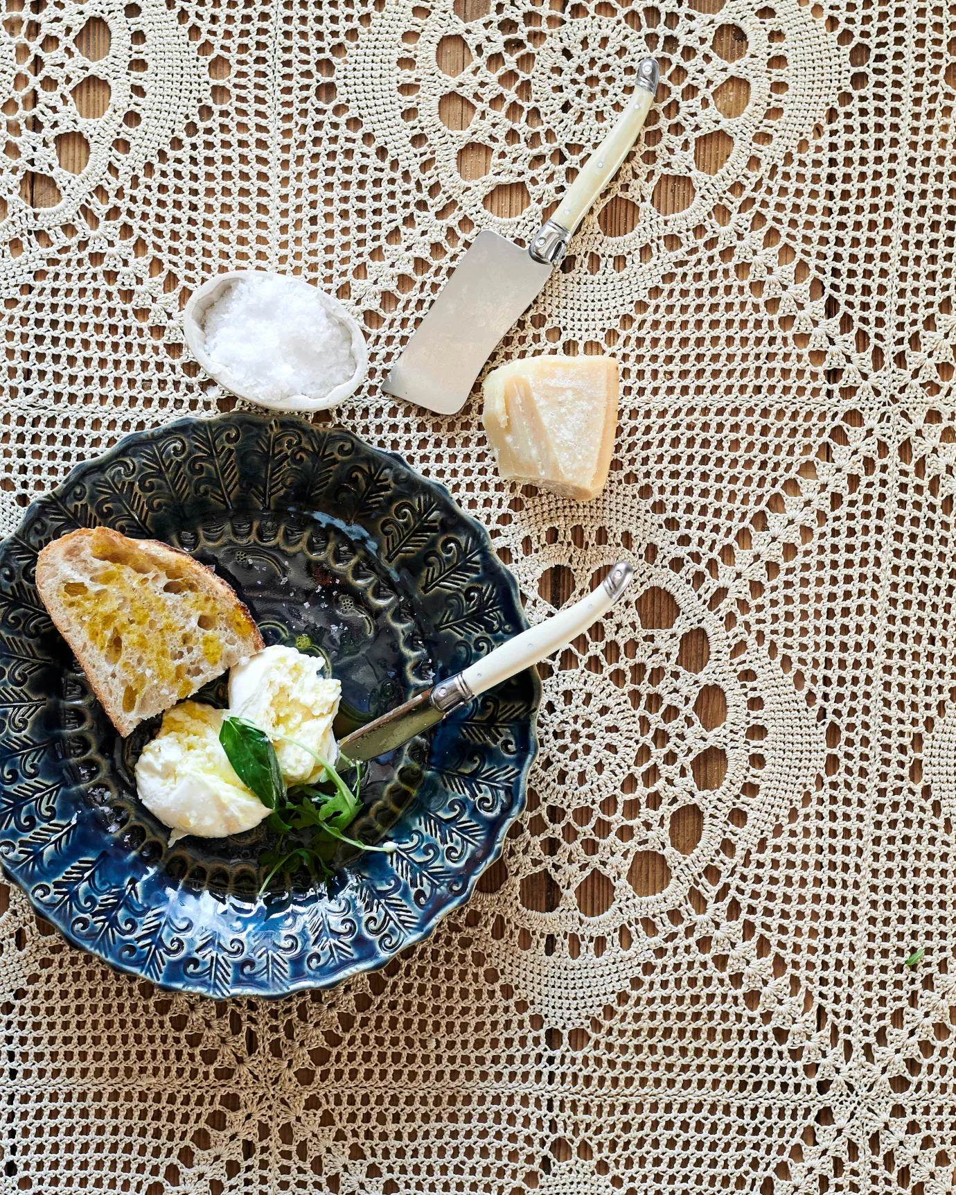 An Indigo Blue Platter with bread, cheese and poached eggs on a vintage crocheted tablecloth.