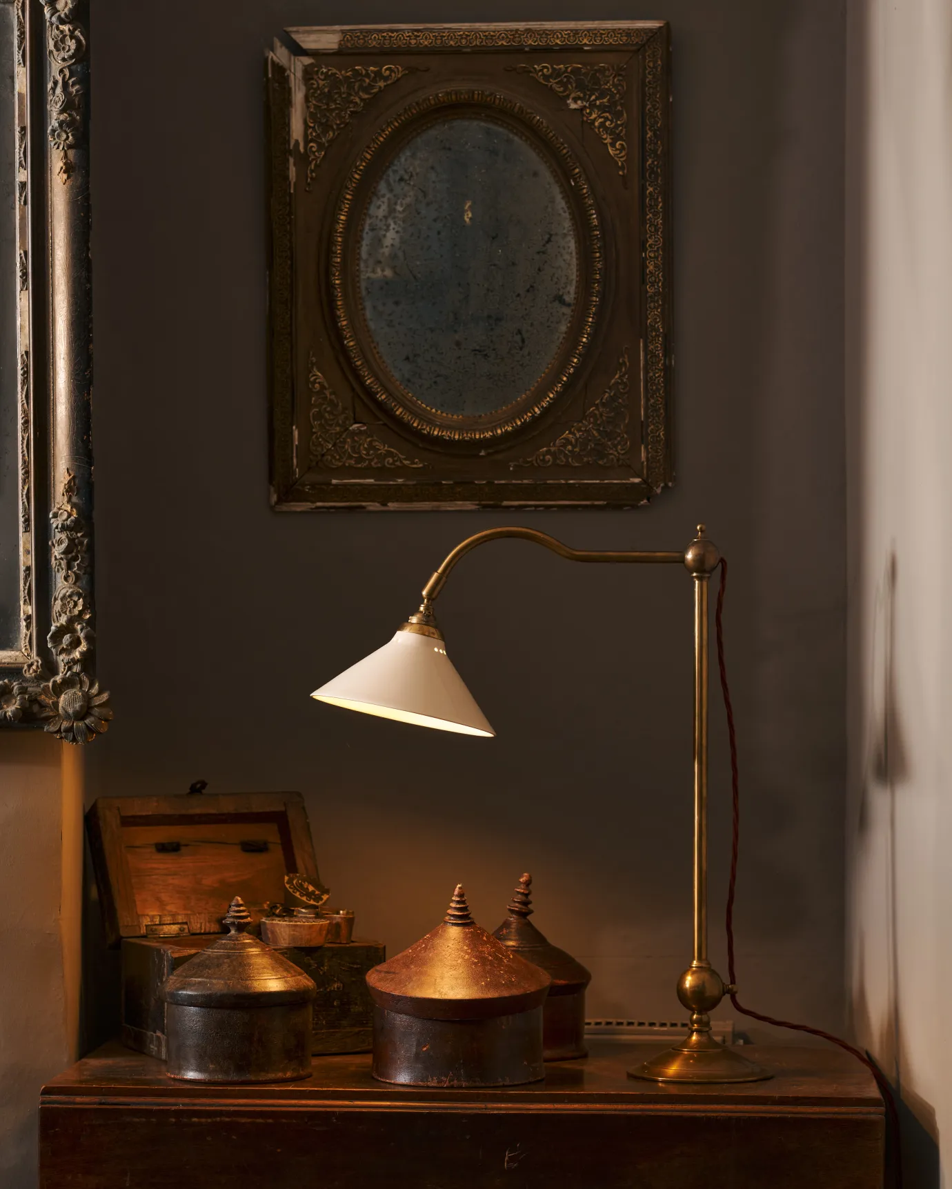 The Grand Tour Desk Lamp on a wooden dresser, illuminating the room.