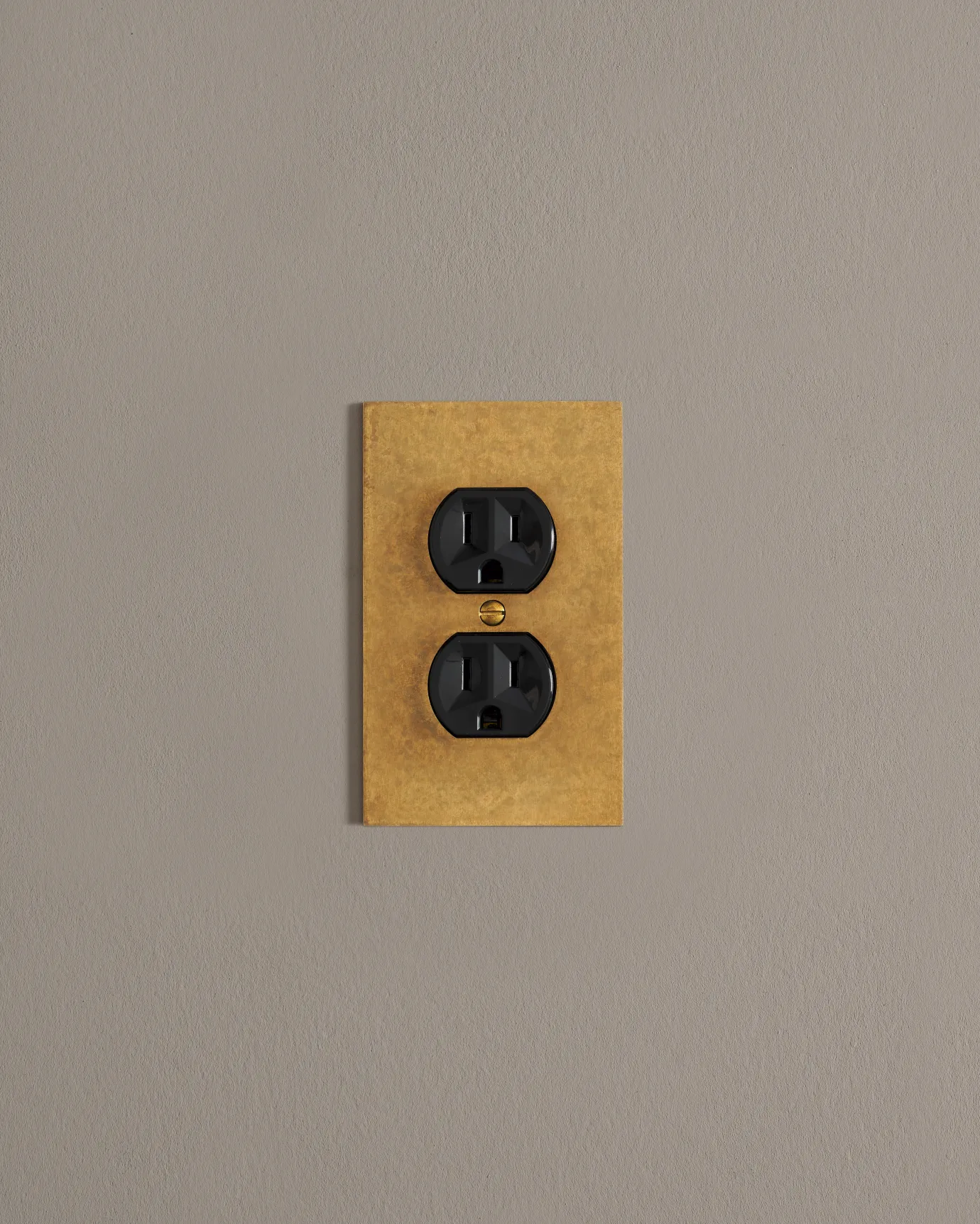 A front on shot on a duplex outlet on an aged brass cover plate.