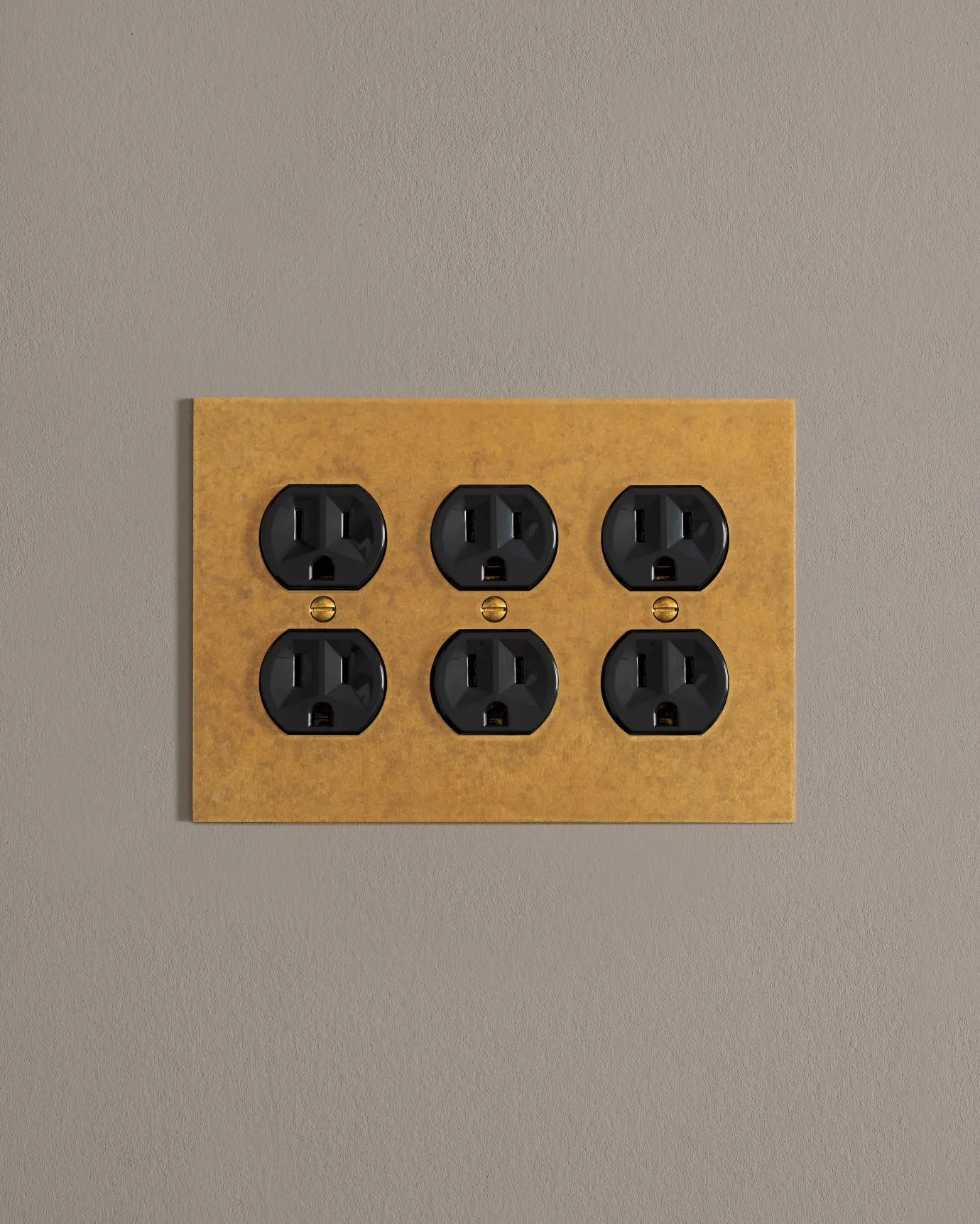 A front on shot on a duplex outlet on an aged brass cover plate.
