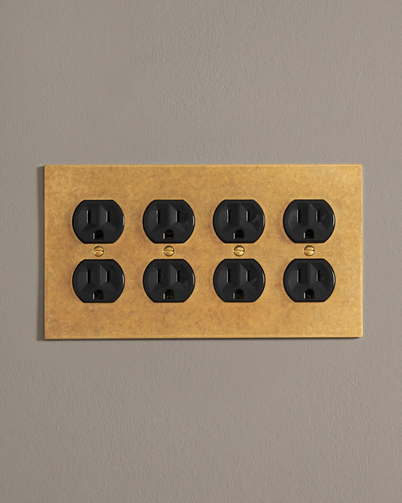 A front on shot on a duplex outlet on an aged brass cover plate.