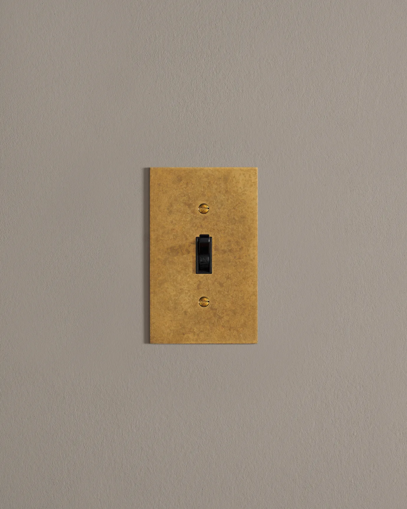 A front on shot on a toggle switch on an aged brass cover plate.