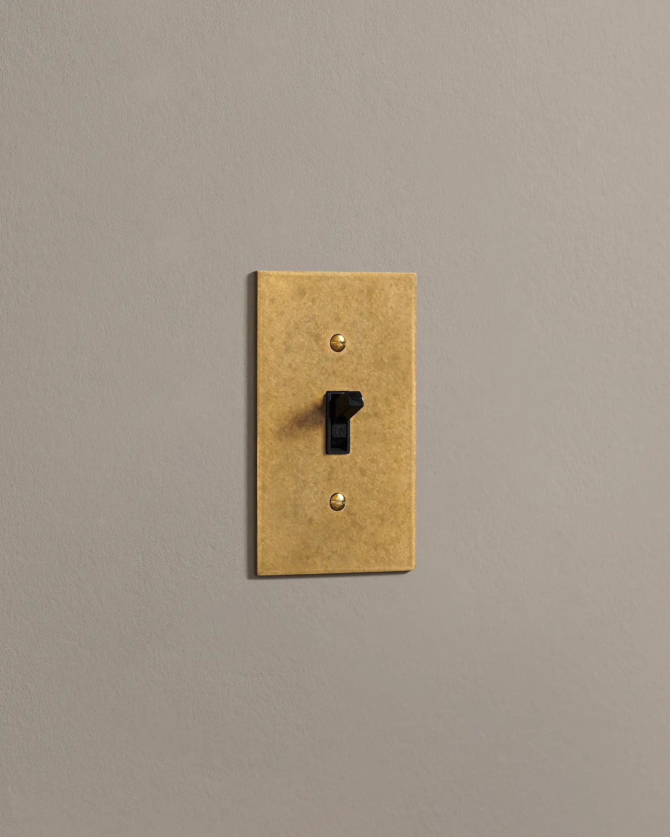 A side on shot on a toggle switch on an aged brass cover plate.