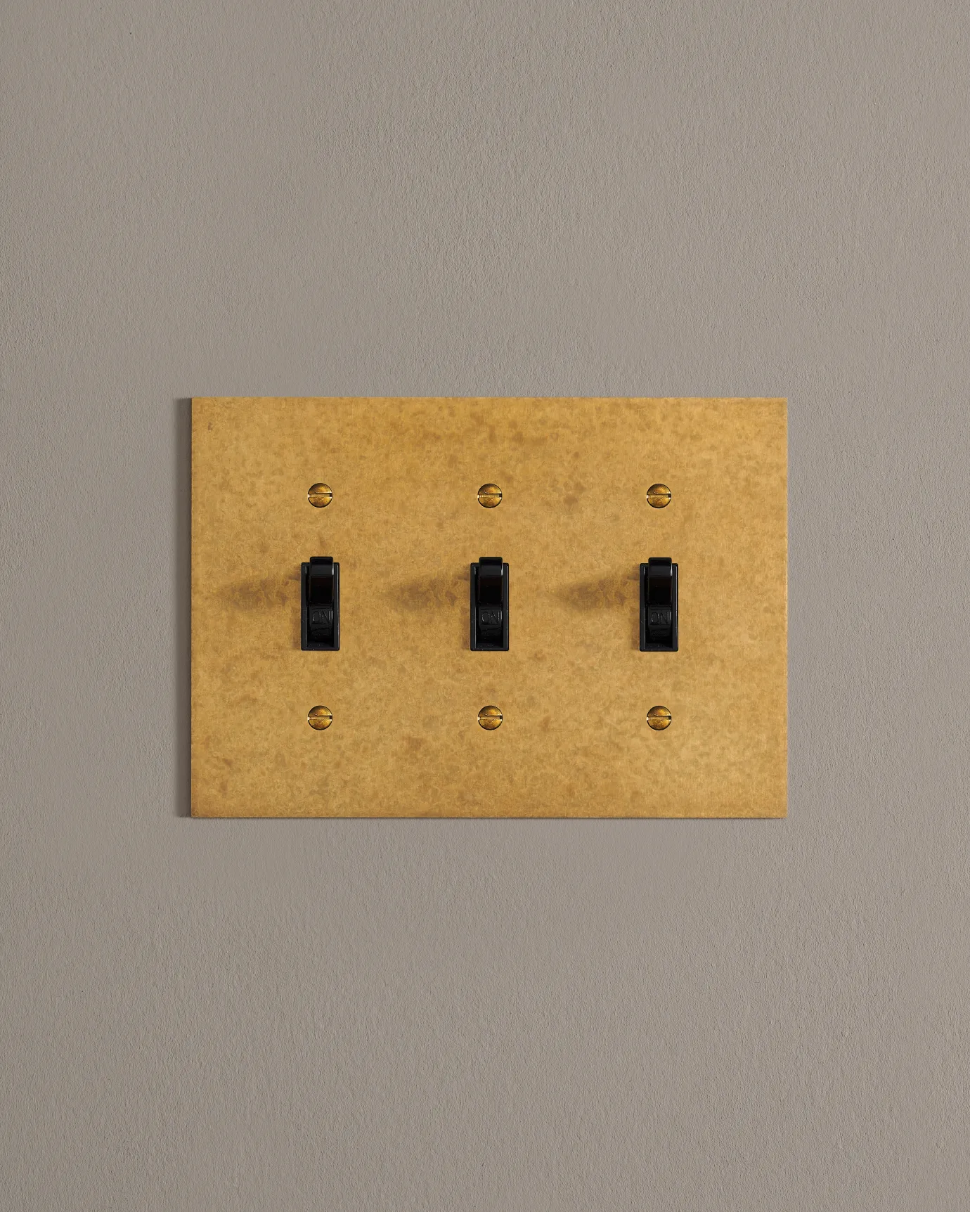 A front on shot on a toggle switch on an aged brass cover plate.