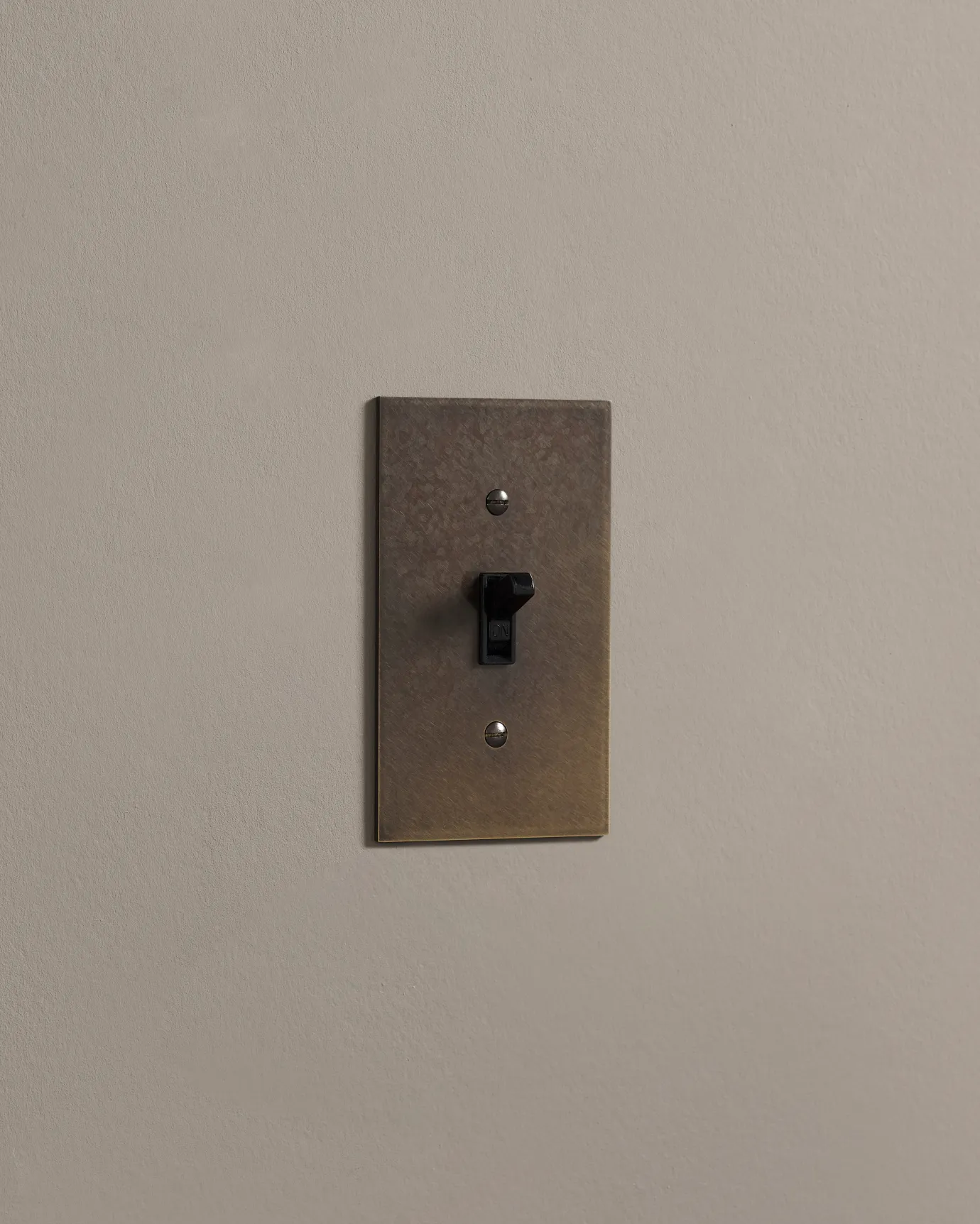 a side on shot of the toggle switch on an oxidised brass cover plate.