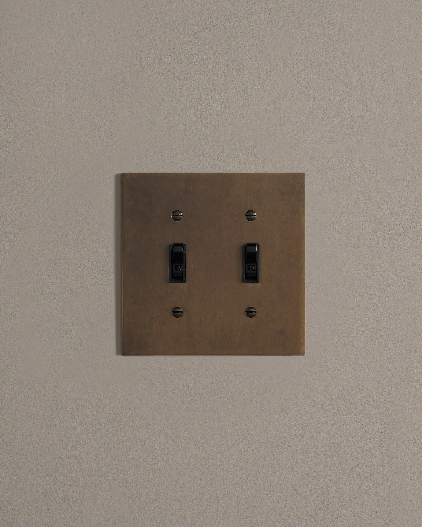 a front on shot of the toggle switch on an oxidised brass cover plate.