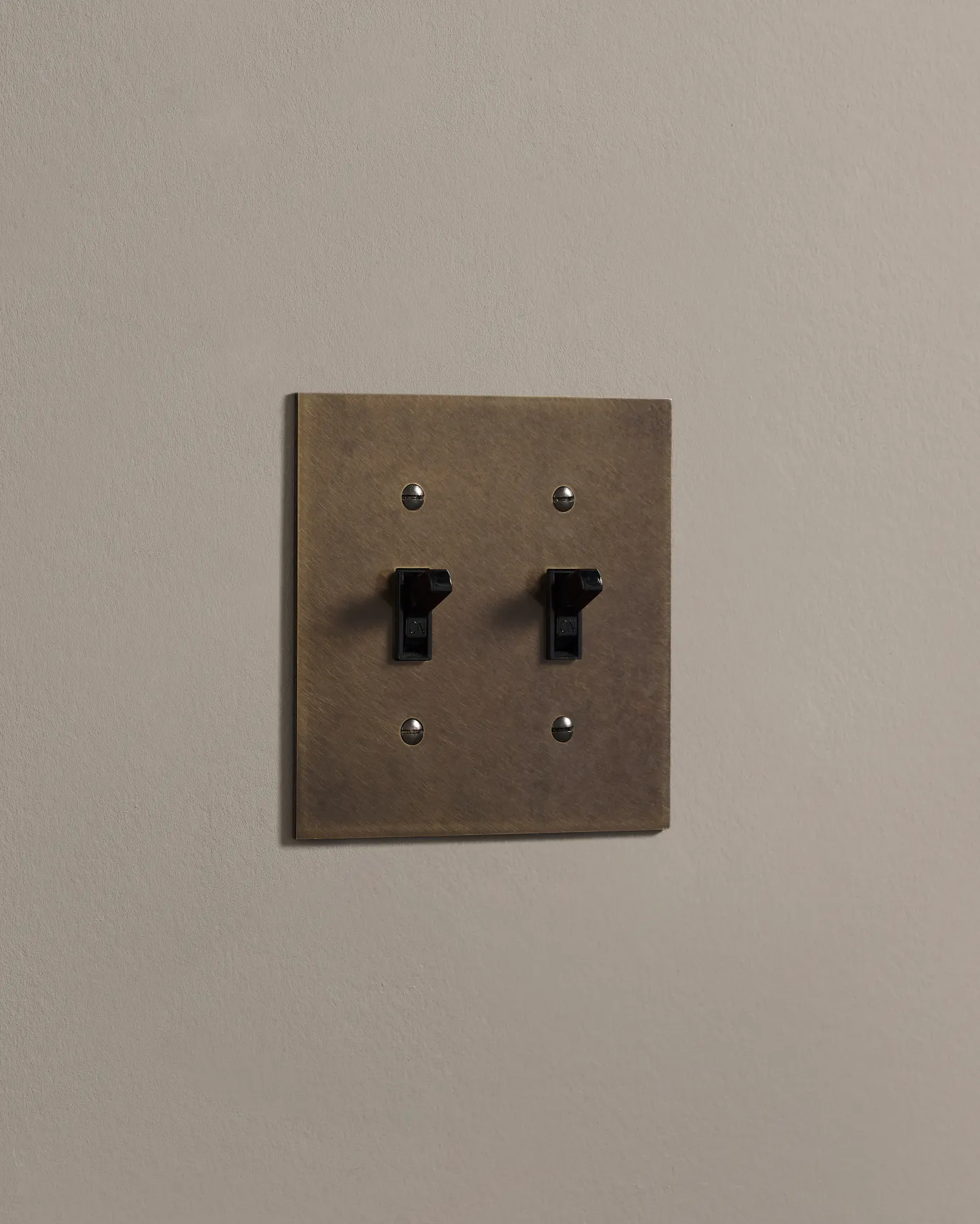 a side on shot of the toggle switch on an oxidised brass cover plate.