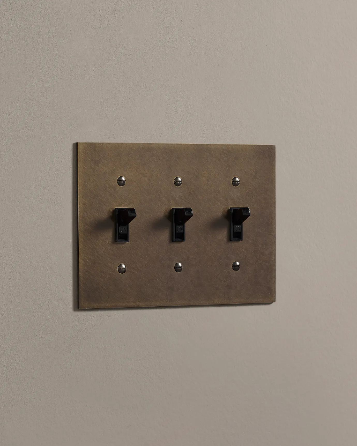 a side on shot of the toggle switch on an oxidised brass cover plate.