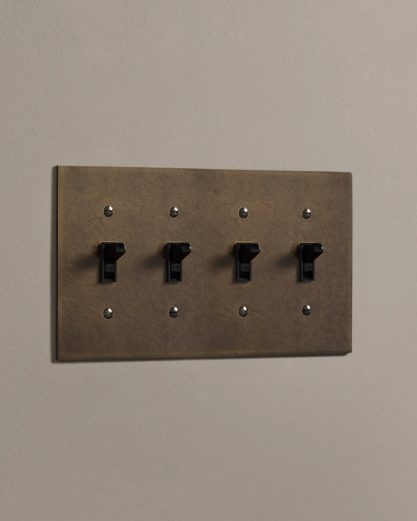 a side on shot of the toggle switch on an oxidised brass cover plate.