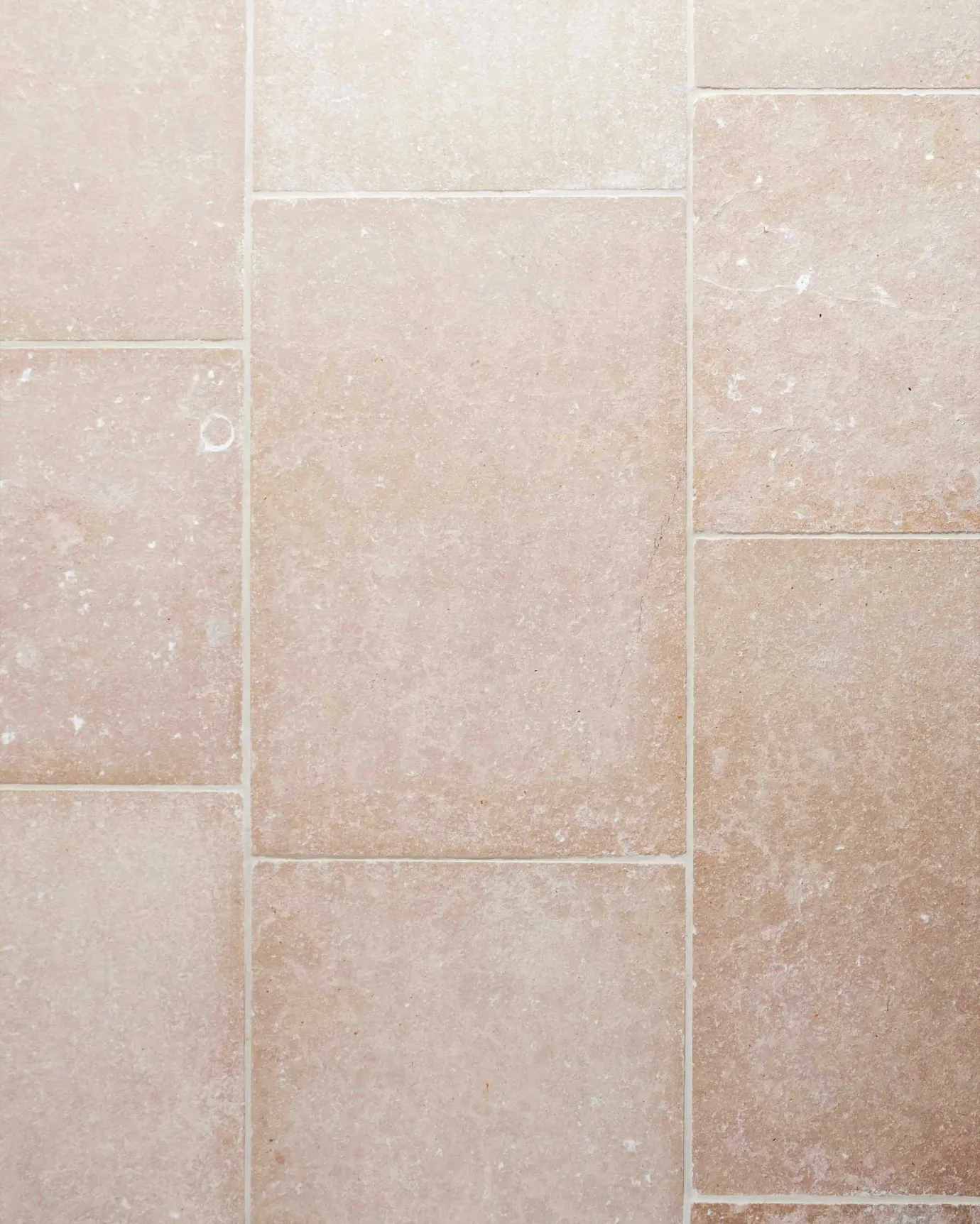 An overhead view of a soft creamy pink coloured limestone floor with a lightly textured surface.